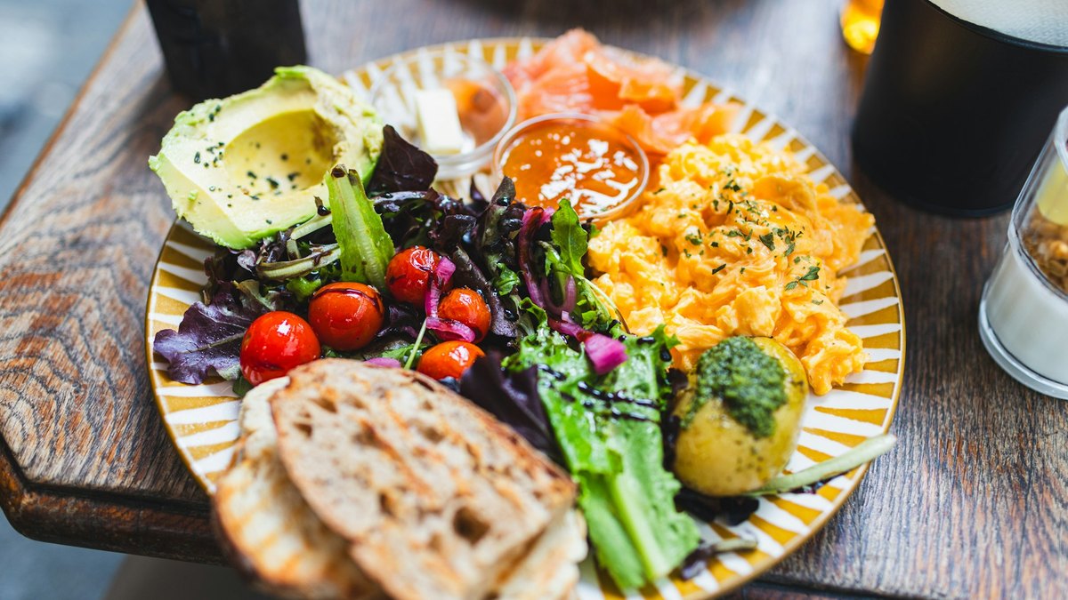 Śniadaniowy talerz z awokado, jajkami, łososiem i zieleniną