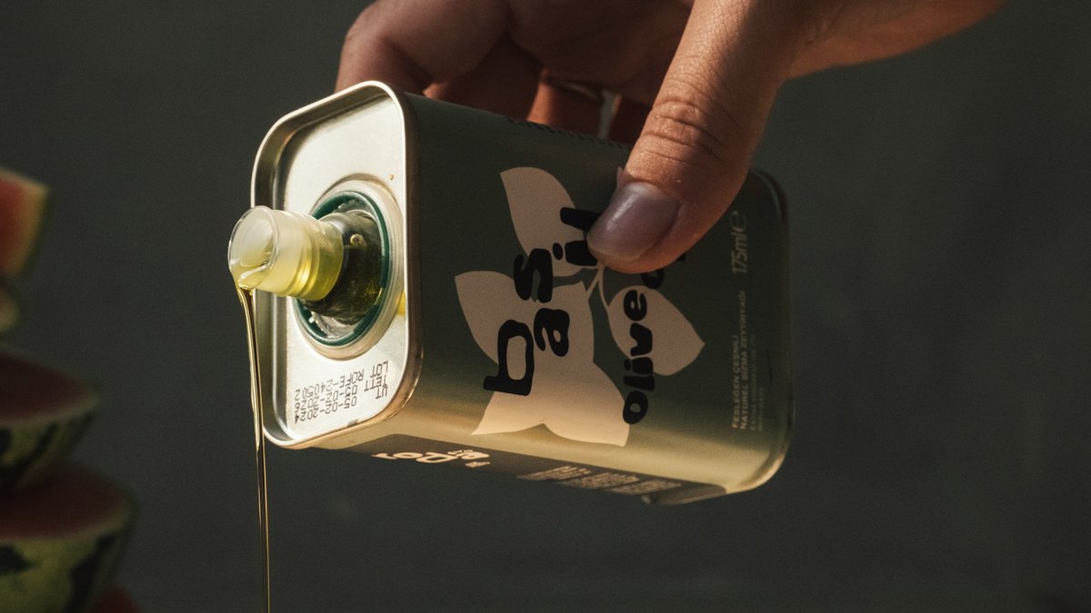 Dłoń nalewająca oliwę na sałatkę caprese z pomidorami i bazylią