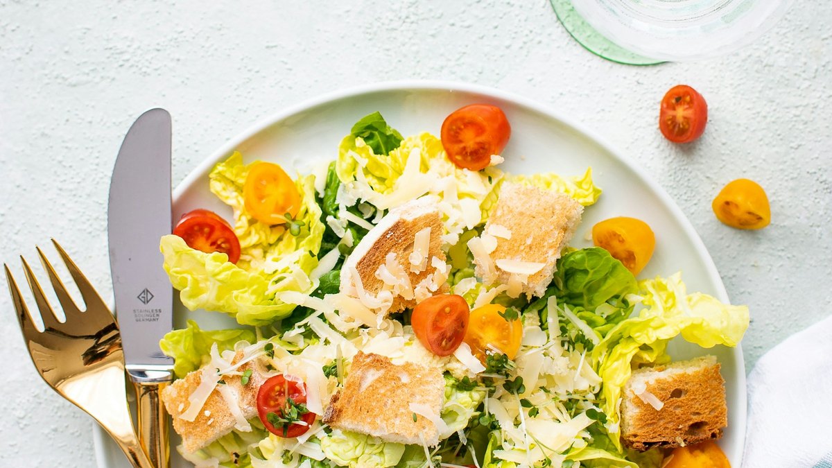 Sałatka z pomidorami, sałatą i grzankami na jasnym tle